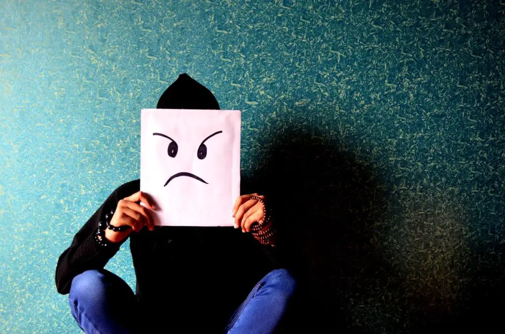 This image shows a man holding up an angry face to show that he's resentful. It's used for the article "I do everything for my girlfriend and get nothing in return". 