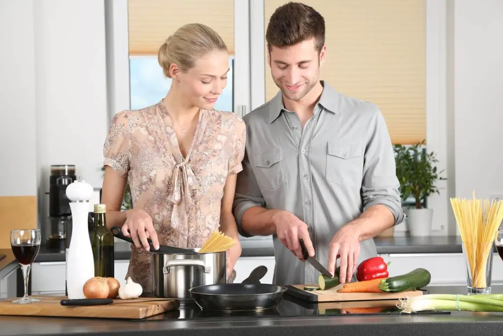 This image shows a man helping his wife cook. It's used for the article, My boyfriend hasn't said I love you in 9 months 