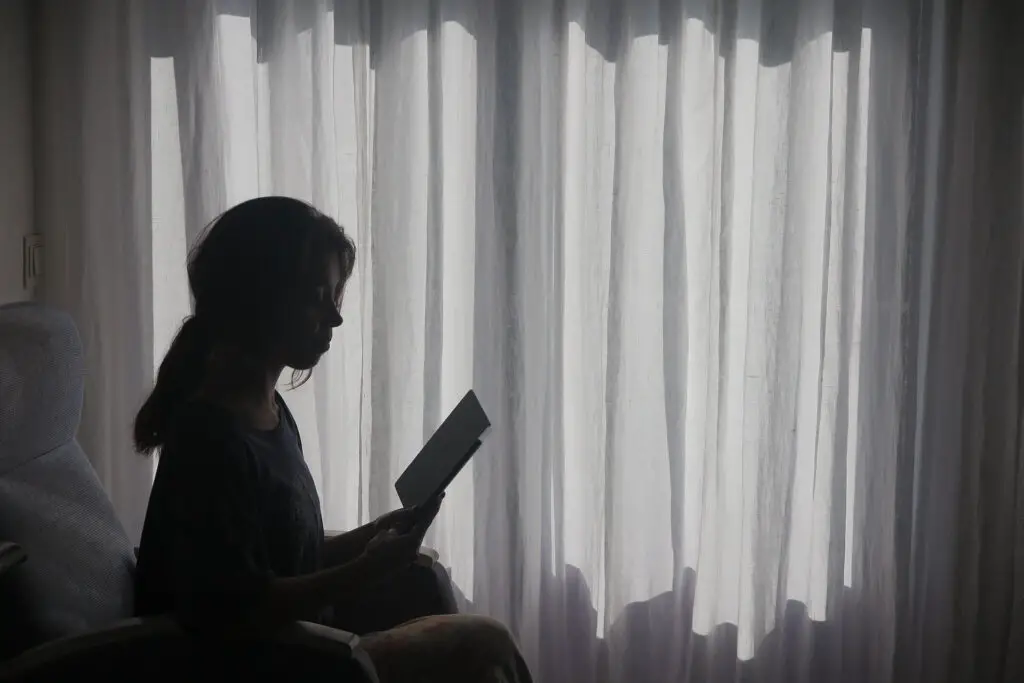 This image shows a woman reading. It's used in the article "how to stop overthinking in a long-distance relationship"