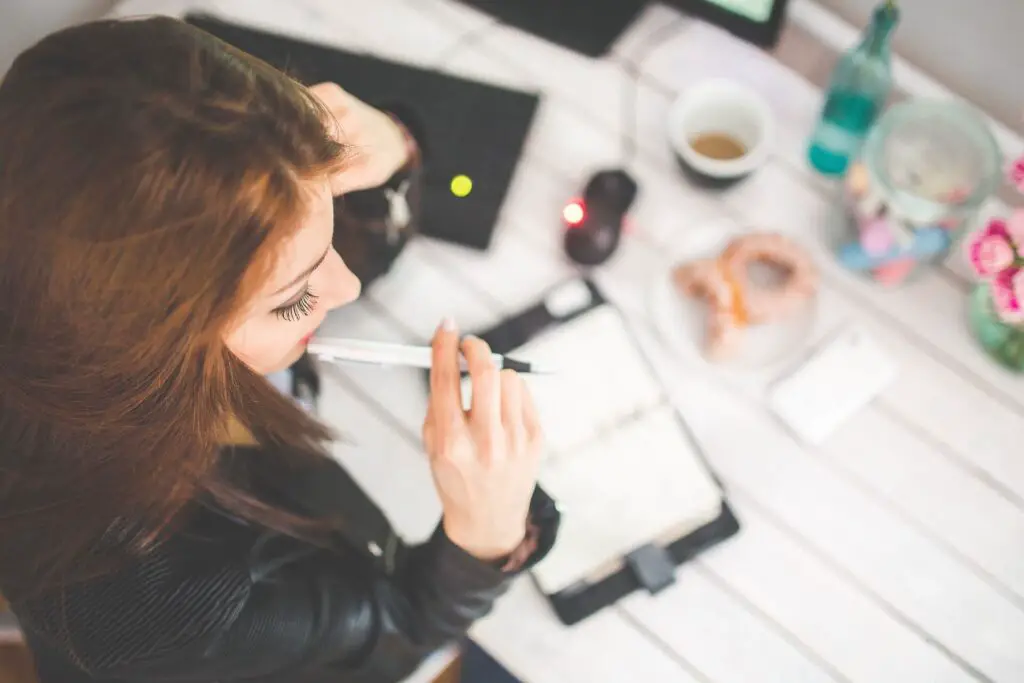 This image shows a woman writing on her journal her strengths. It's used for the article "jealousy in a long-distance relationship"