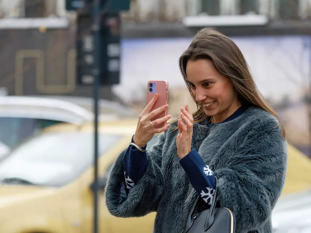 This image shows a woman using her phone. It's used for the article "long distance relationships apps" 