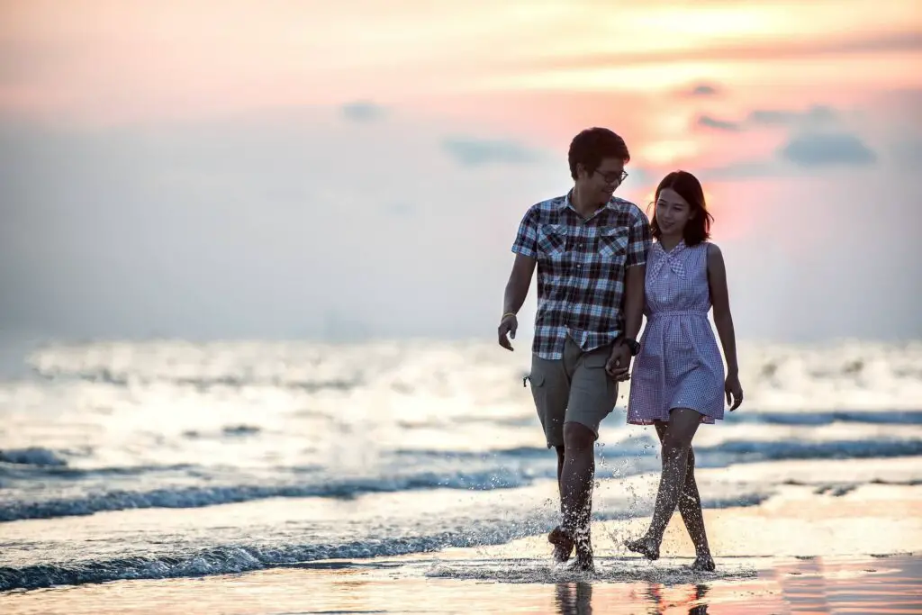 This image shows a couple walking on the beach holding hands. It's used for the article "Funny questions to ask on a date"